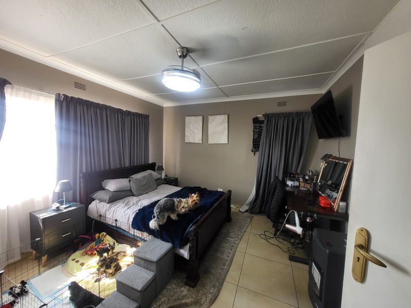 A functional bedroom featuring tiled flooring, a central ceiling fan, and neutral wall tones, providing a comfortable and practical living space.