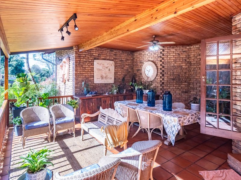 Spacious covered patio featuring a timber-clad ceiling, exposed brick walls, and terracotta tiling, providing a comfortable outdoor entertainment area with built-in cabinetry.