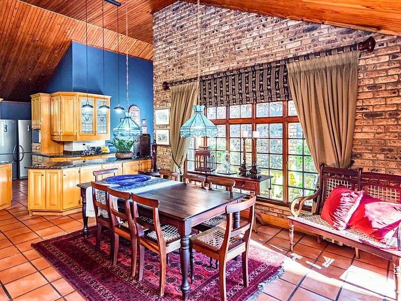 Open-plan kitchen and dining area featuring exposed brick walls, timber raked ceilings, terracotta flooring, and traditional timber cabinetry with granite countertops.