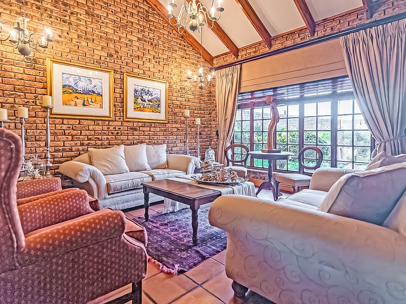A cozy living room featuring exposed brick walls, vaulted ceilings with timber beams, and large windows that provide ample natural light.