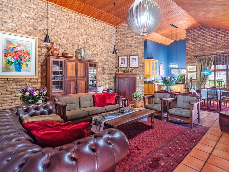 Spacious open-plan living and dining area featuring high vaulted timber ceilings, exposed brick walls, and terracotta flooring, seamlessly connecting to the kitchen.
