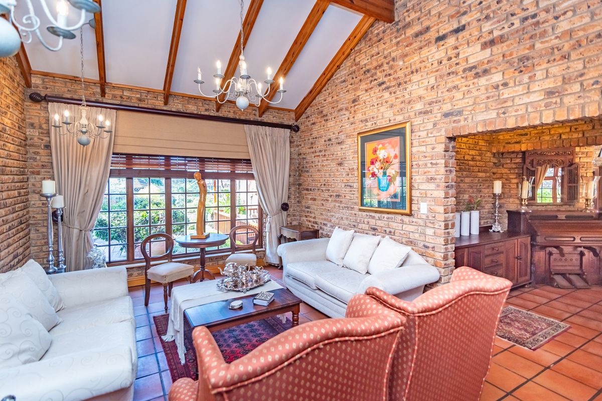 Spacious living room featuring exposed brick walls, a vaulted timber beam ceiling, and large timber-framed windows that provide ample natural light.
