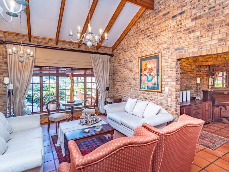 Spacious living room featuring exposed brick walls, a vaulted timber beam ceiling, and large timber-framed windows that provide ample natural light.