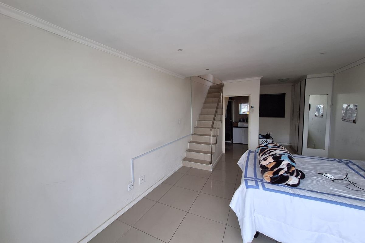A bedroom featuring tiled flooring, built-in cupboards, and an internal staircase leading to an upper level.