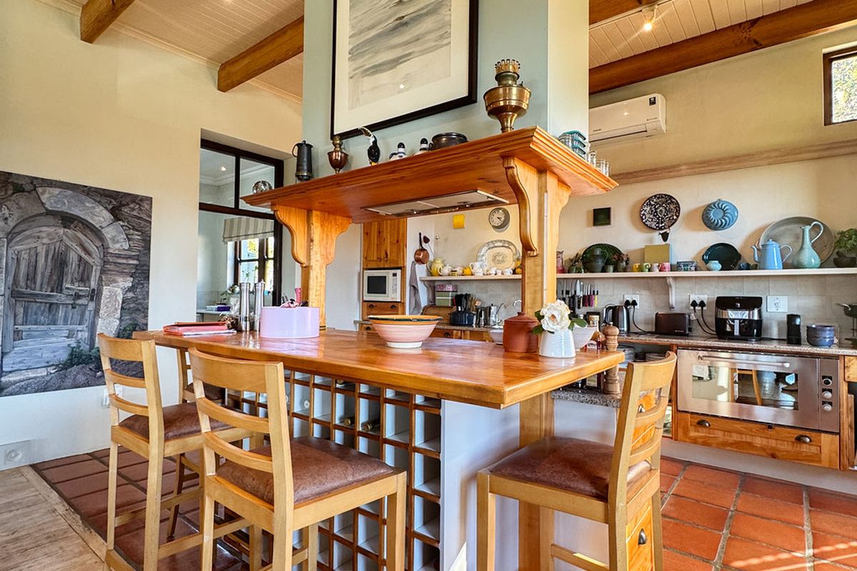 A rustic-style kitchen featuring exposed timber beams, terracotta flooring, and a central island with a built-in wine rack and breakfast bar seating.