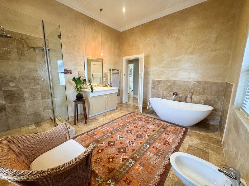 Spacious bathroom featuring a freestanding bathtub, walk-in shower, vanity unit, and bidet, finished with elegant travertine tiling and high ceilings.