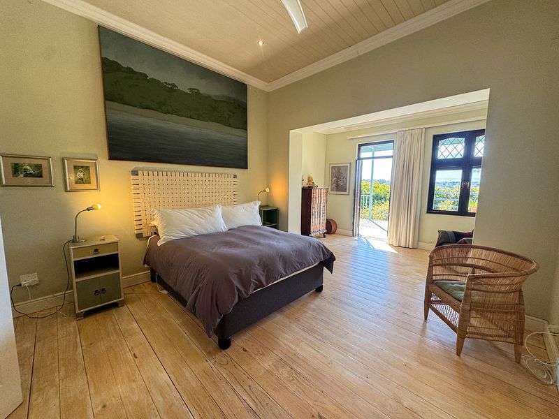 Spacious bedroom featuring light timber flooring, a classic tongue and groove ceiling, and direct access to a private balcony through a glass door.