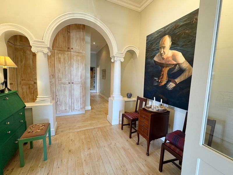 A spacious hallway featuring elegant architectural archways, decorative columns, polished timber flooring, and integrated built-in cabinetry.