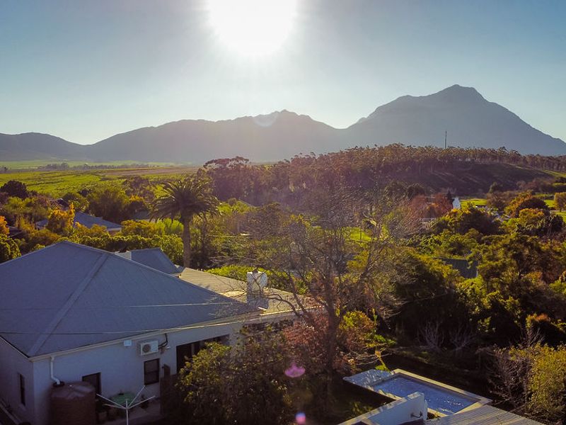 Aerial view of the property featuring a pitched roof, swimming pool, and scenic mountain landscape backdrop.