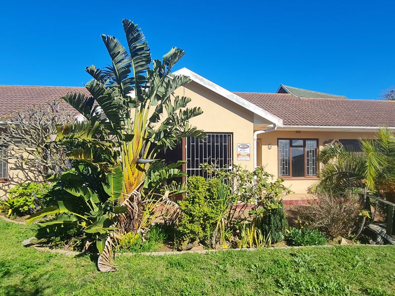 Front elevation of a single-story residential house featuring a tiled roof, security bars on windows, and a well-established front garden.