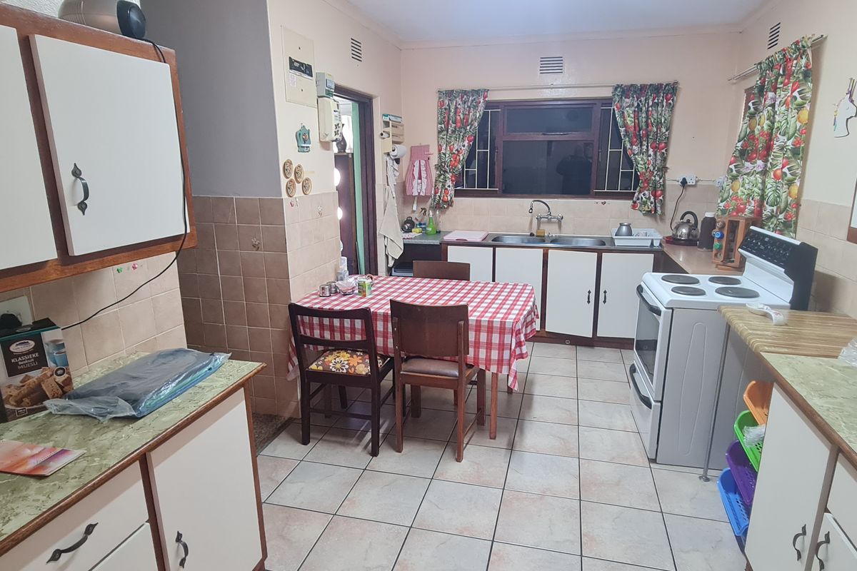 A functional kitchen featuring tiled flooring, laminate countertops, a double basin sink, and ample built-in cabinetry with a classic layout.