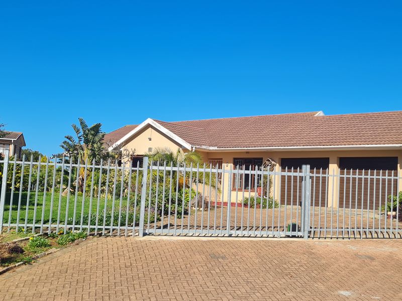 Front view of a single-story house featuring a paved driveway, double garage, and secure steel palisade fencing.