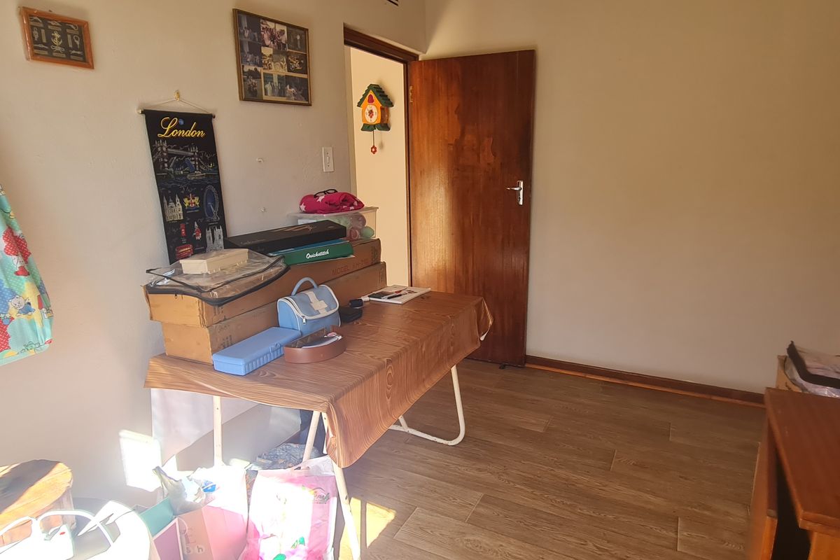 A bedroom featuring laminate flooring and a wooden door, providing a functional space ready for personalization.