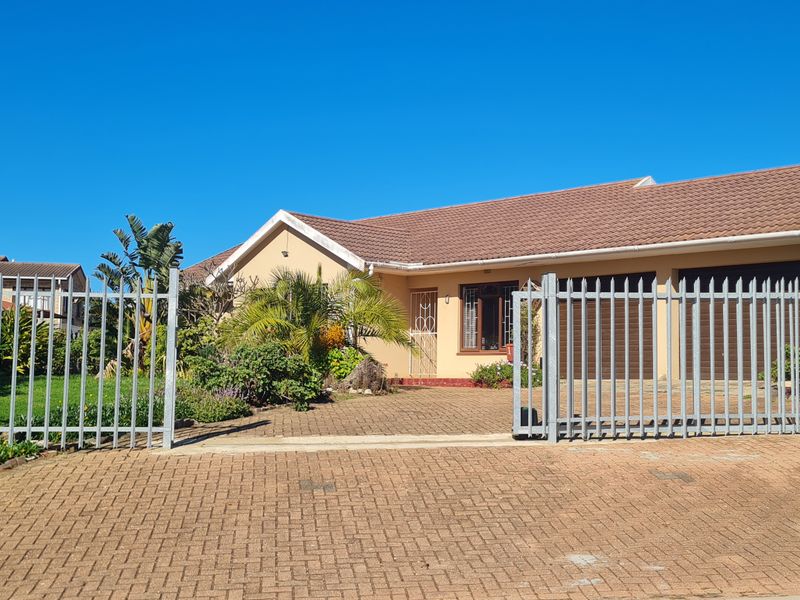 Front elevation of a single-story house featuring a paved driveway, double garage, and secure perimeter fencing.