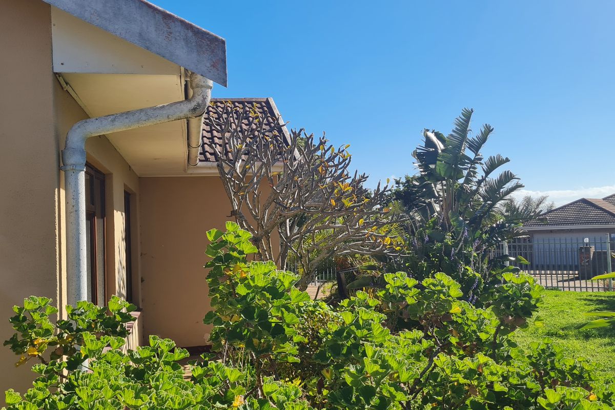 A view of the rear exterior of the house featuring established garden landscaping, roof tiles, and guttering.