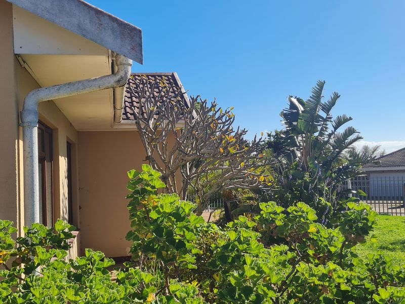 A view of the rear exterior of the house featuring established garden landscaping, roof tiles, and guttering.