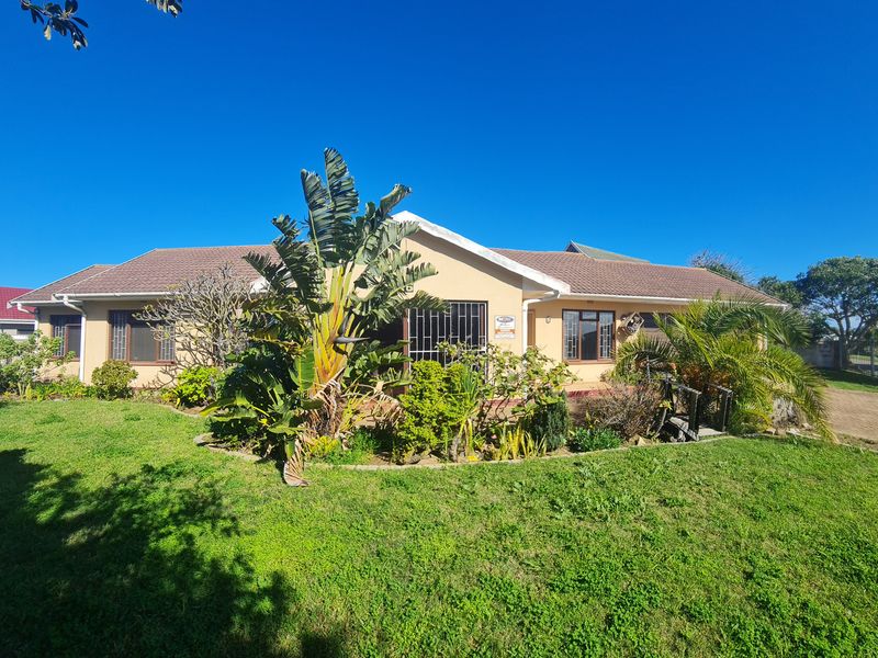 A front view of a single-story residential house featuring a tiled roof, security bars on windows, and a well-maintained front garden with a paved driveway.