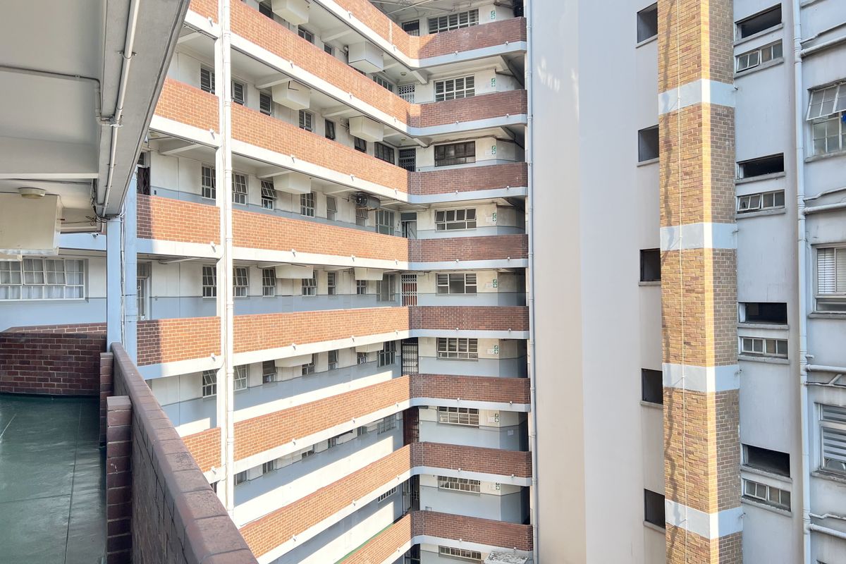 View of the apartment building exterior, showcasing the brick facade, multi-level balcony walkways, and external building infrastructure.