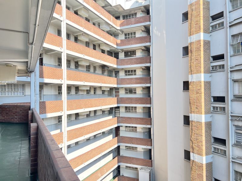 View of the apartment building exterior, showcasing the brick facade, multi-level balcony walkways, and external building infrastructure.