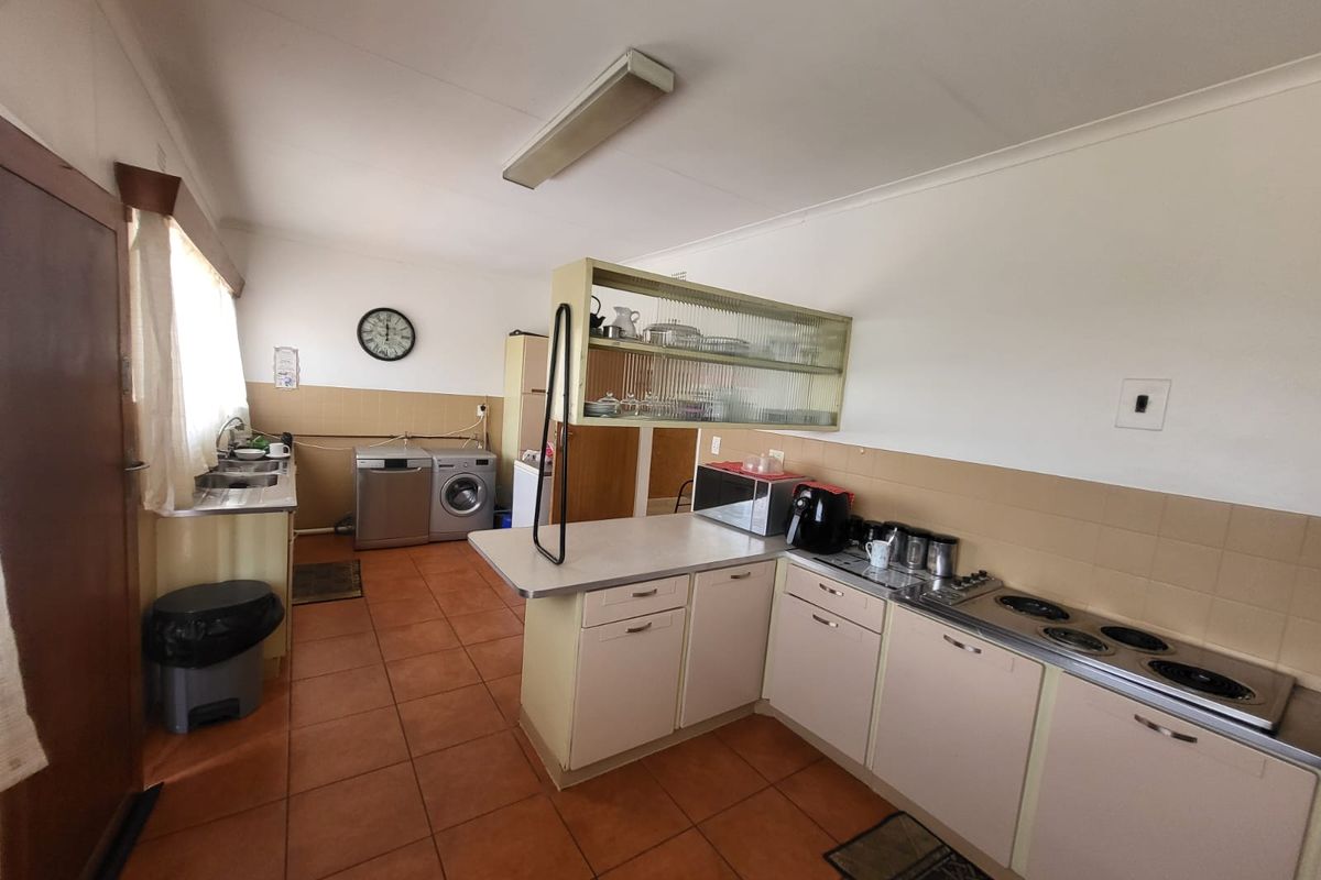Functional kitchen featuring built-in cabinetry, laminate countertops, an electric hob, and tiled flooring, offering a practical layout with integrated laundry appliance space.