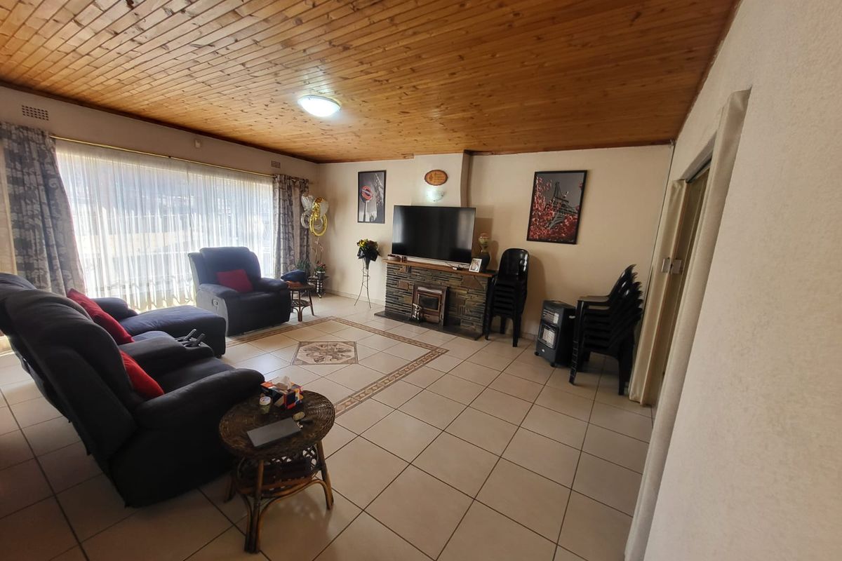 Spacious living room featuring a timber-clad ceiling, tiled flooring, and a stone-clad fireplace, providing a comfortable and functional family space.