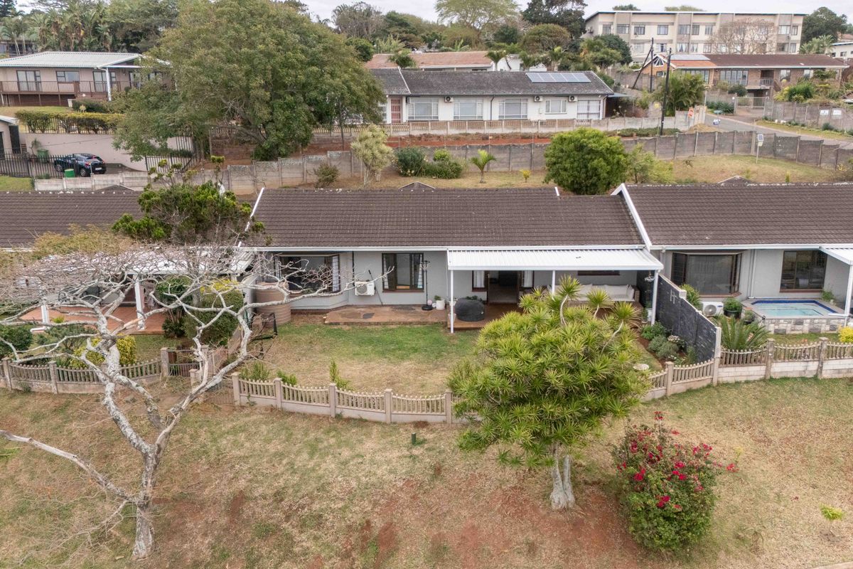 Aerial view of a townhouse complex featuring a tiled roof, private garden, covered patio, and a small swimming pool.