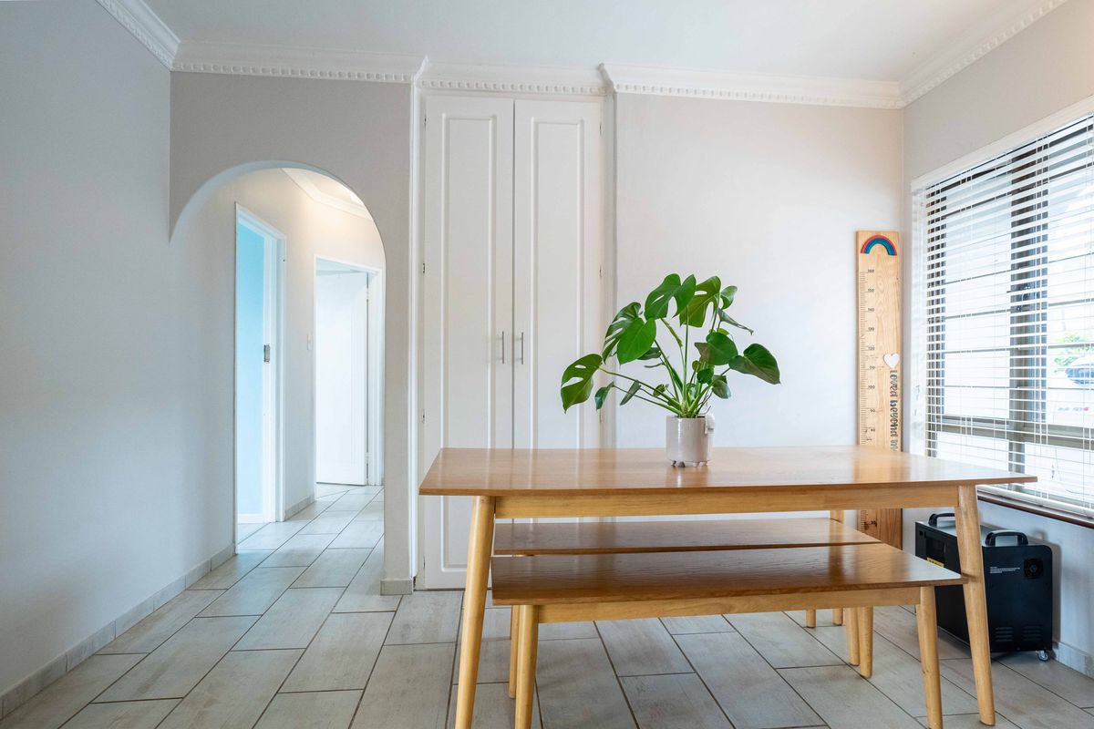 A bright living area featuring tiled flooring, built-in storage cupboards, an elegant archway, and crown molding, providing a clean and well-maintained space.