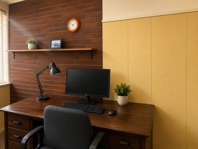 A home office space featuring a distinctive exposed brick wall, timber wall paneling, and a floating timber shelf.