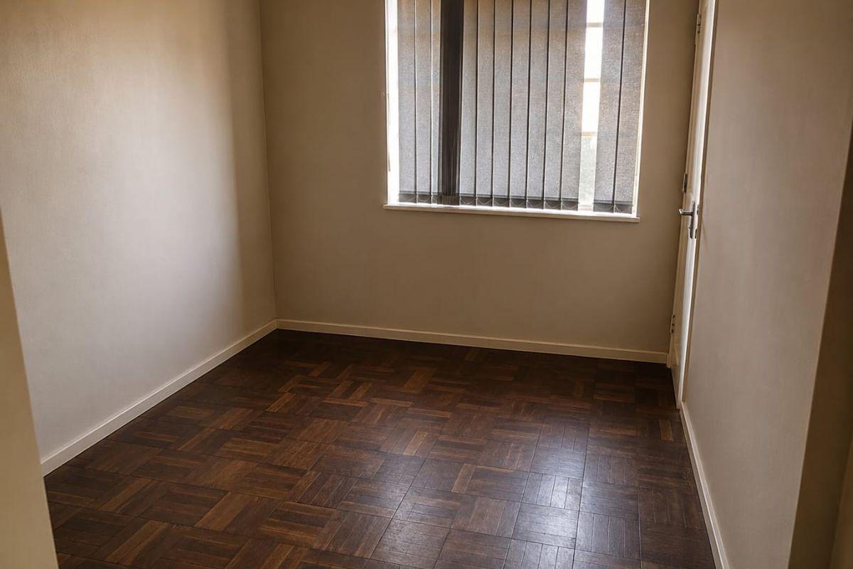 An empty bedroom featuring dark parquet flooring and vertical window blinds, offering a neutral canvas for interior design.