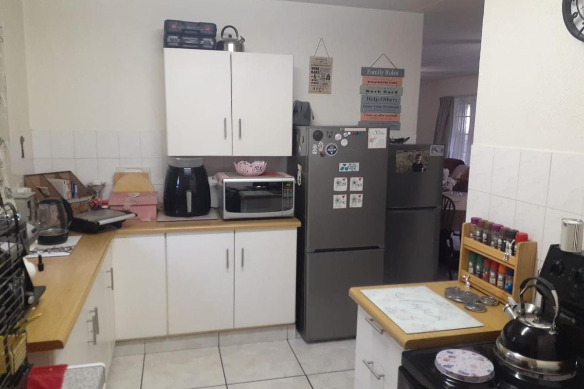 A functional kitchen featuring white cabinetry, laminate countertops, tiled backsplash, and tiled flooring, providing a practical workspace for daily meal preparation.