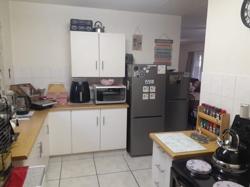 A functional kitchen featuring white cabinetry, laminate countertops, tiled backsplash, and tiled flooring, providing a practical workspace for daily meal preparation.