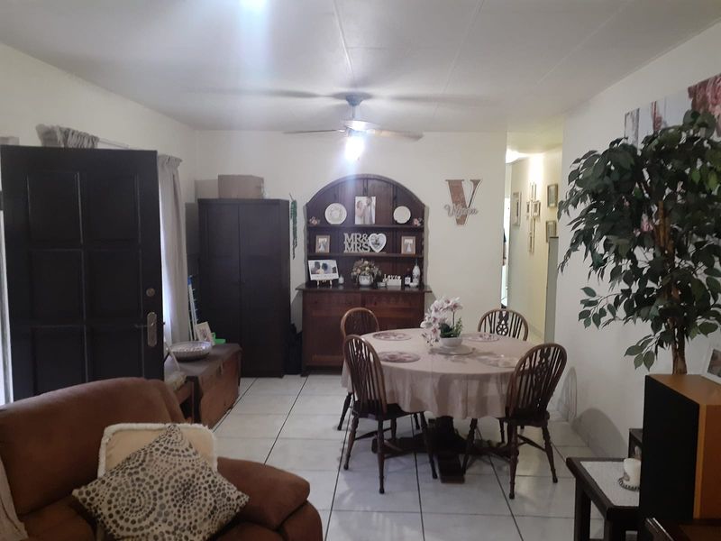 A living and dining area featuring tiled flooring and a ceiling fan, providing a functional space for daily living.