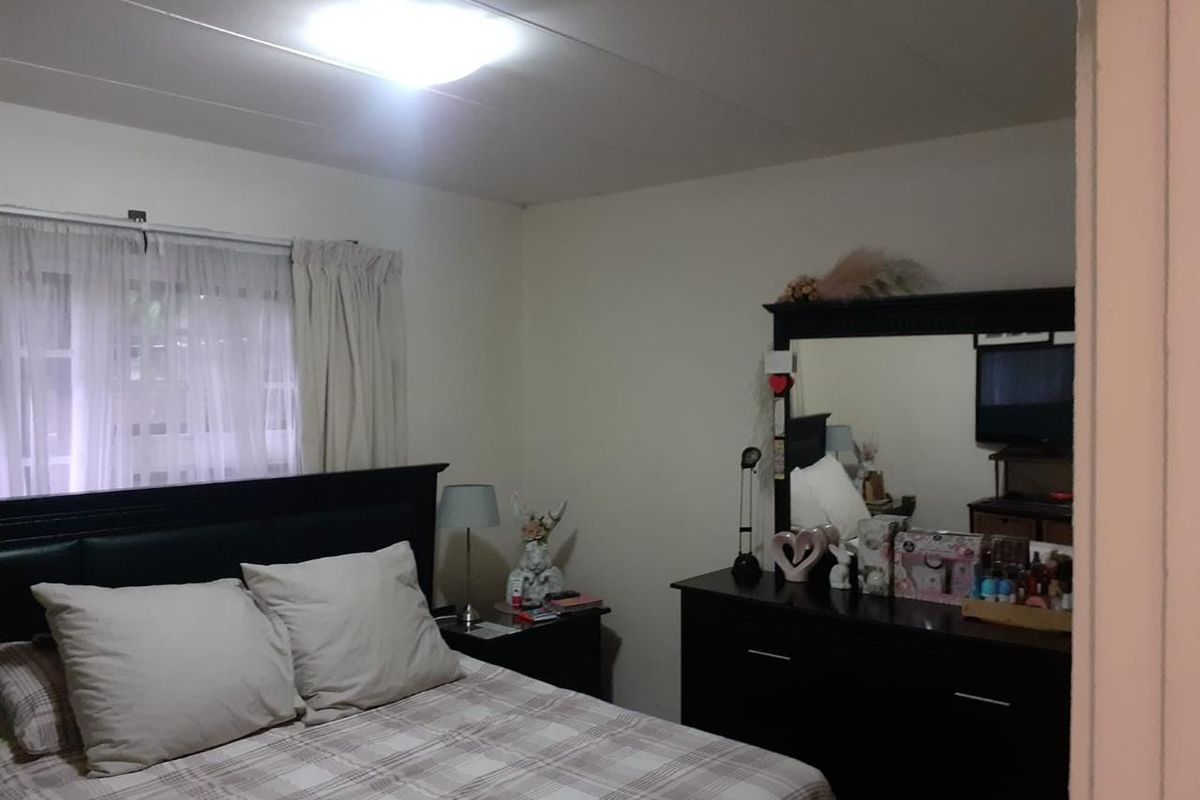 A standard bedroom featuring a window with curtains and a central ceiling light fixture.