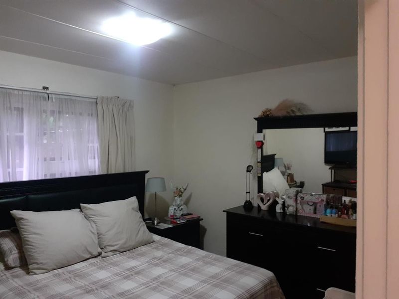A standard bedroom featuring a window with curtains and a central ceiling light fixture.