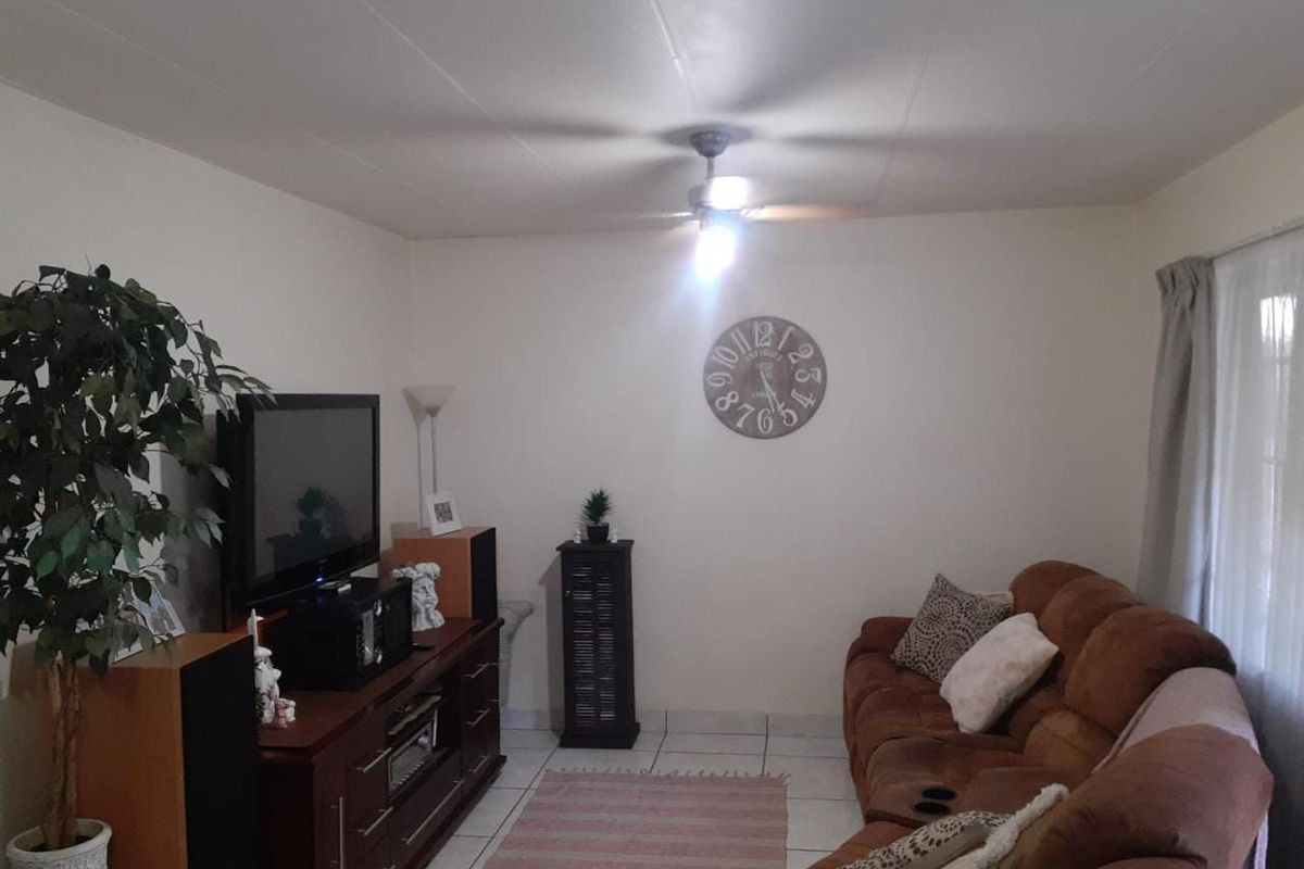 A living room featuring tiled flooring and a ceiling fan, providing a functional and comfortable space for relaxation.