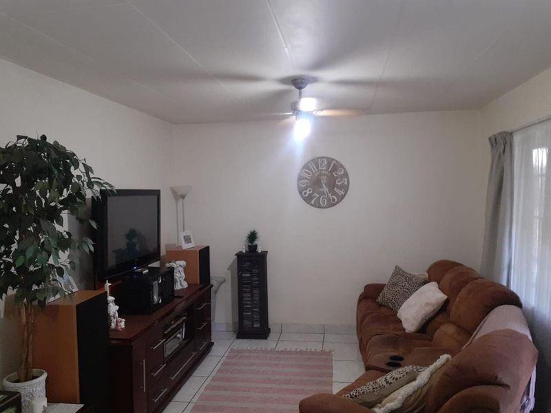 A living room featuring tiled flooring and a ceiling fan, providing a functional and comfortable space for relaxation.