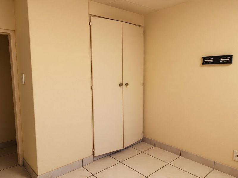 An empty bedroom featuring tiled flooring and a built-in cupboard, providing a neutral space ready for personalization.