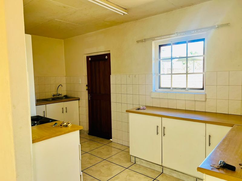 A functional kitchen featuring laminate countertops, tiled backsplash, and built-in cabinetry, offering a blank canvas for potential modernization and renovation.
