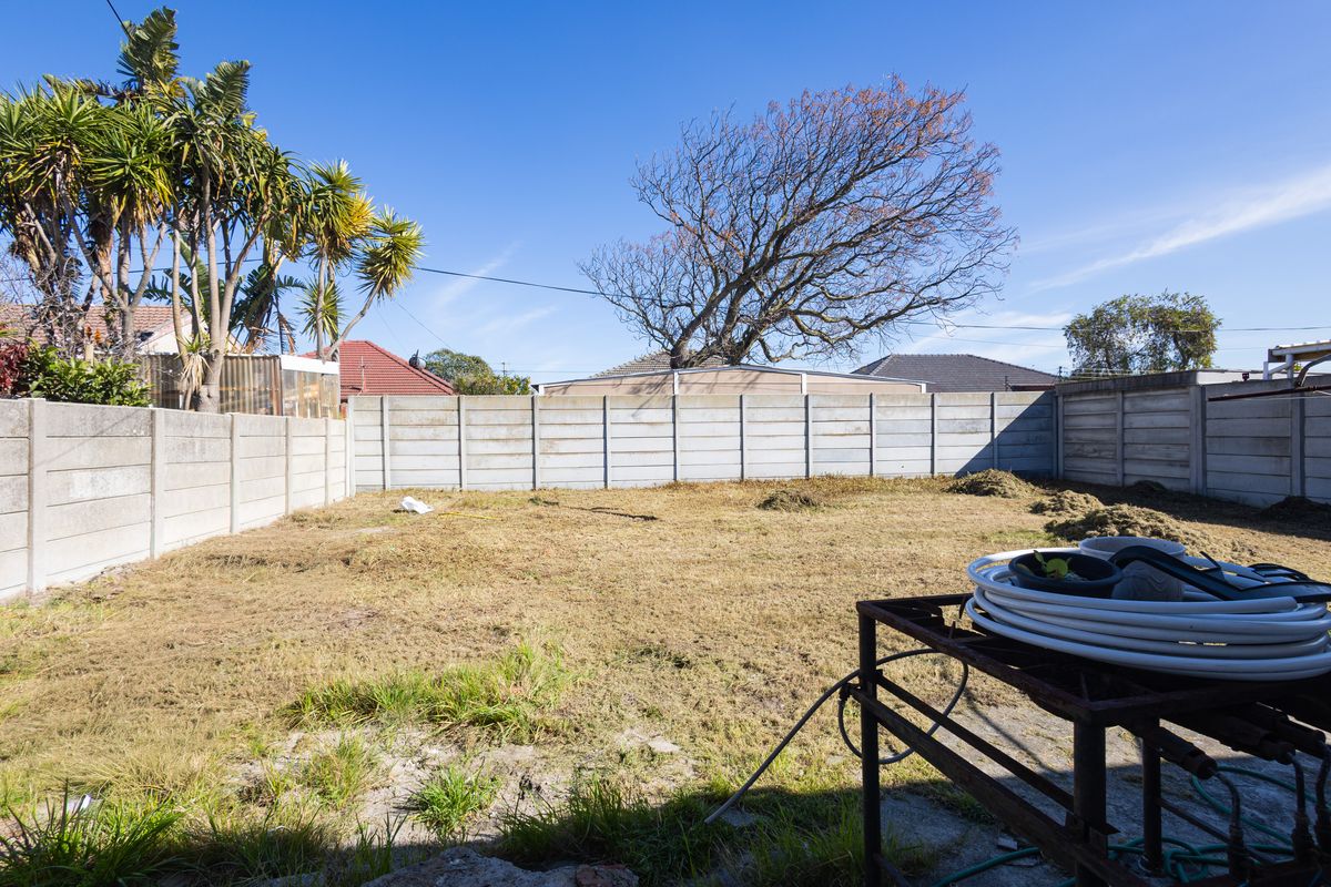 A spacious, open rear garden area enclosed by precast concrete boundary walls, offering a blank canvas for landscaping potential.