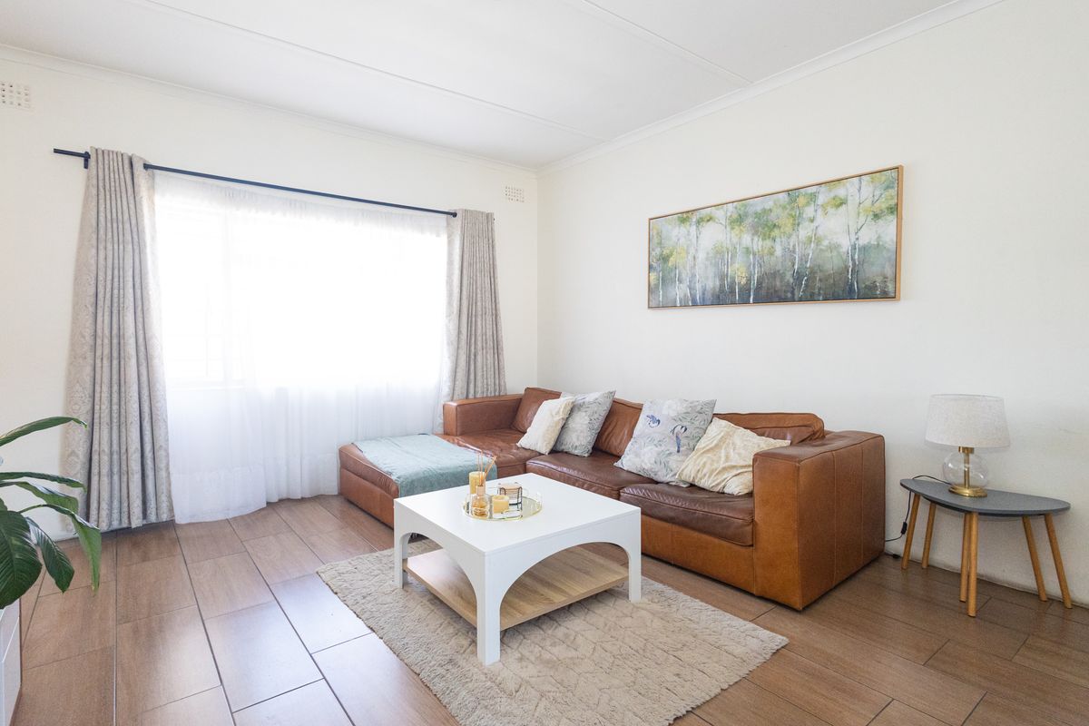 A bright and well-maintained living room featuring modern tiled flooring and clean white walls, offering a comfortable and inviting space.