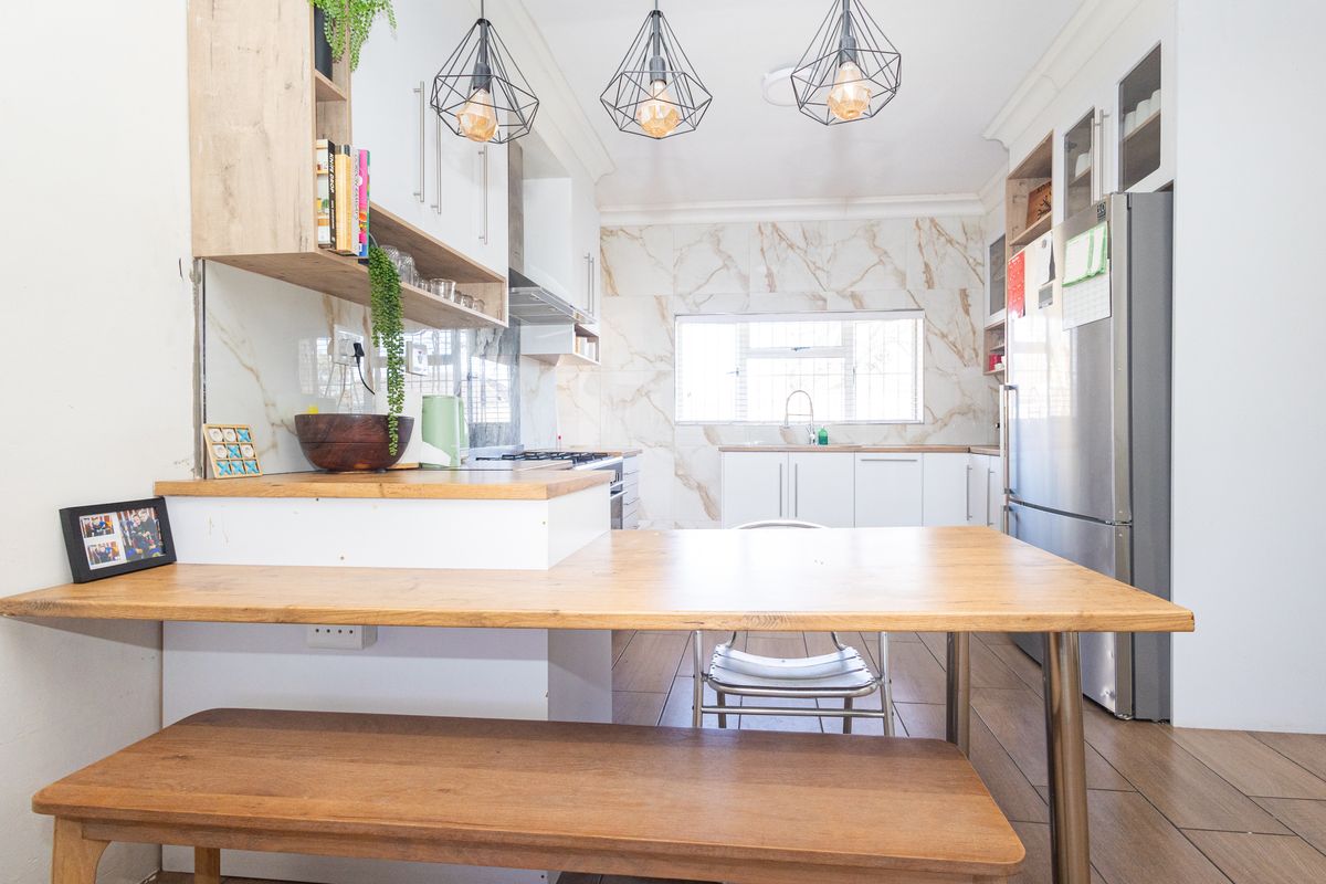 Modern kitchen featuring marble-look splashbacks, timber-look floor tiles, built-in cabinetry, and contemporary pendant lighting, creating a bright and functional culinary space.