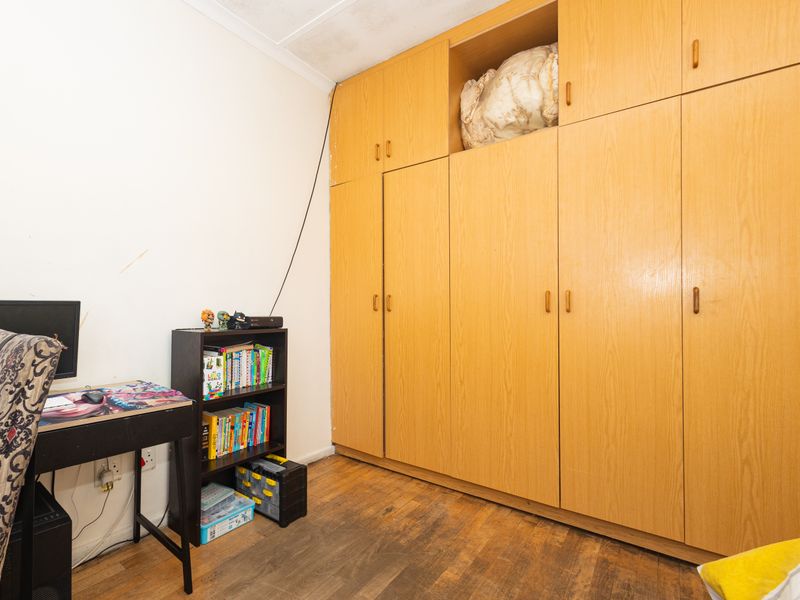 Bedroom featuring extensive floor-to-ceiling built-in wooden cupboards and laminate flooring, offering ample storage space.