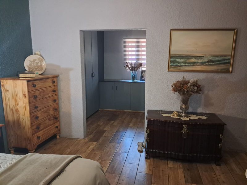 Bedroom featuring wood-look tile flooring and a walk-through area with built-in storage cupboards.