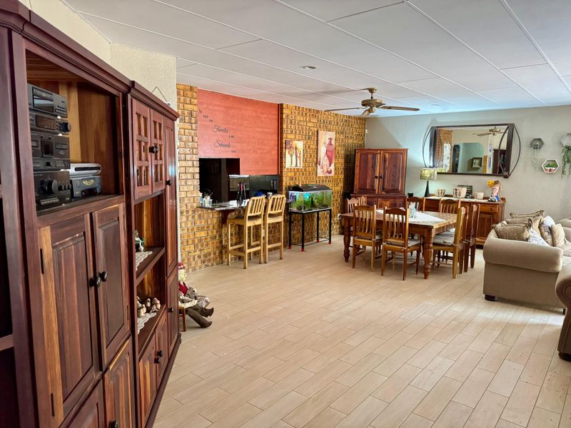 Spacious open-plan living and dining area featuring exposed brick walls, tiled flooring, and a built-in bar counter with recessed lighting.