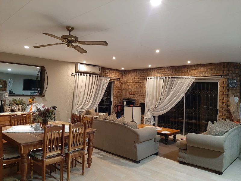 Spacious open-plan living and dining area featuring exposed brick walls, recessed lighting, a ceiling fan, and sliding glass doors leading to the exterior.