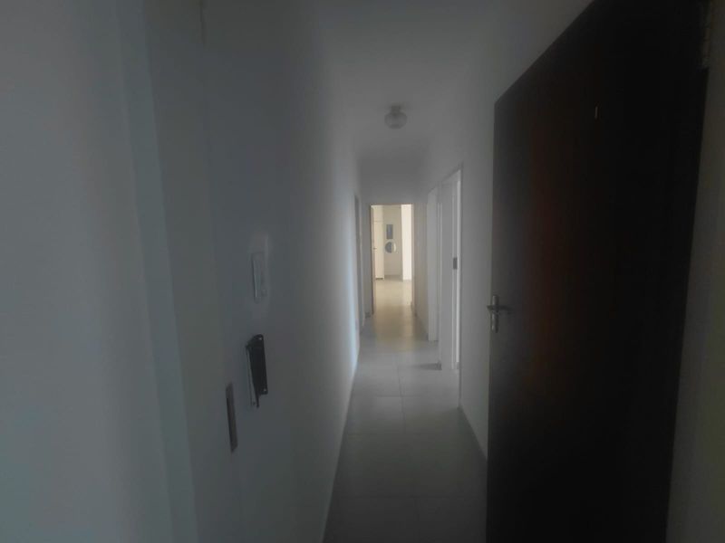 A simple, empty hallway featuring tiled flooring and neutral walls, providing access to multiple rooms within the property.
