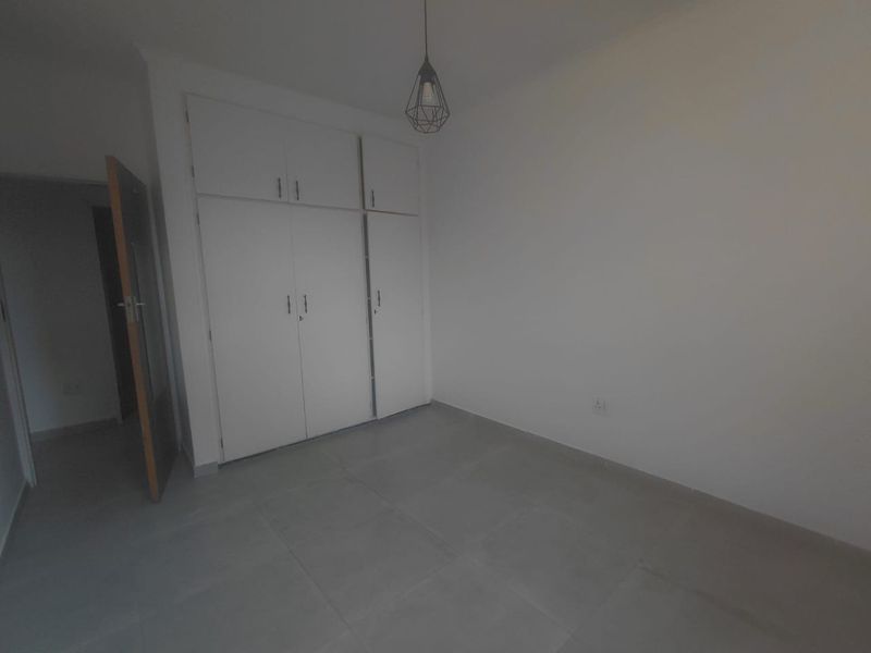 A clean, empty bedroom featuring neutral tiled flooring and white built-in cupboards, providing a blank canvas for personalization.