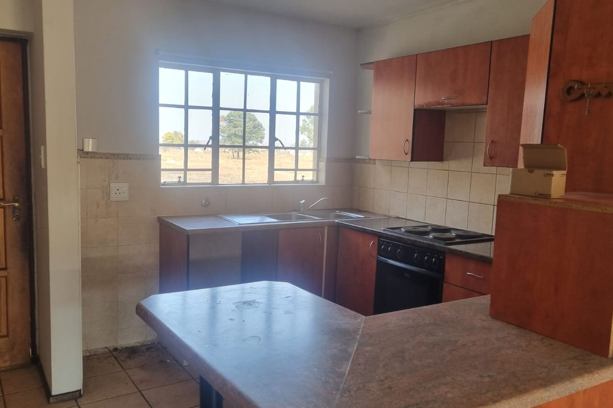 A functional kitchen featuring built-in wooden cabinetry, laminate countertops, a stainless steel sink, and a built-in electric oven with a hob.