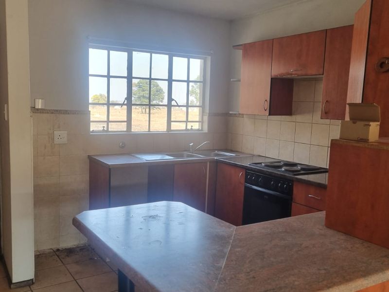 A functional kitchen featuring built-in wooden cabinetry, laminate countertops, a stainless steel sink, and a built-in electric oven with a hob.