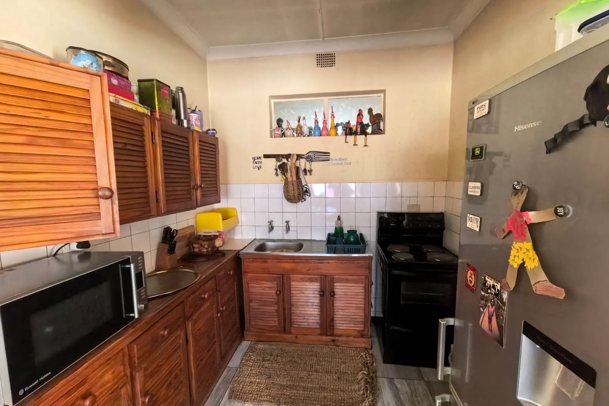 A compact kitchen featuring wooden cabinetry, a tiled backsplash, and a freestanding stove, offering a functional layout with potential for modernization.